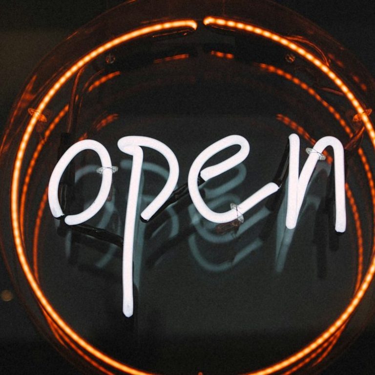 Cartel luminoso que dice "abierto" en letras blancas sobre fondo oscuro. Imagen referida a abierta agencia de Marketing Experience. 